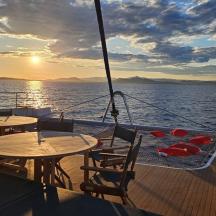 ein Boot mit Tischen und Stühlen und ein Sonnenuntergang auf dem Wasser