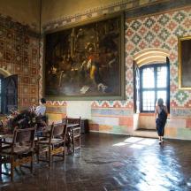a woman walking through a room with tables and a painting