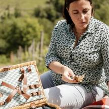 a woman sitting on a blanket next to a picnic basket