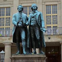 eine Statue von zwei Personen, die vor einem Gebäude stehen