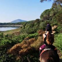 una dona muntant a cavall baixant un turó