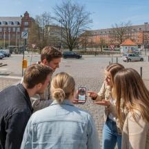 un grup de persones dretes mirant un telèfon mòbil