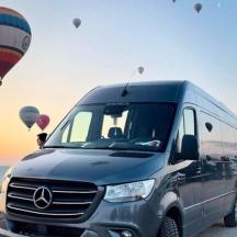 a van parked on the beach with hot air balloons