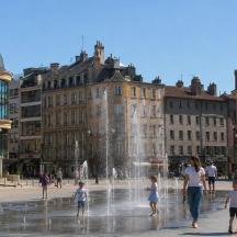a group of people playing in a fountain in a city