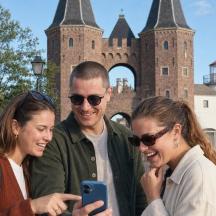 three people looking at a cell phone in front of a castle