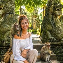 a woman sitting on the steps with two monkeys