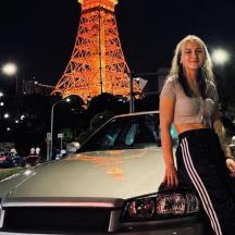 a woman standing next to a car in front of a tower