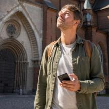 a man standing in front of a building holding a cell phone