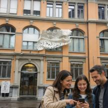 tres persones dretes davant d'un edifici mirant un telèfon mòbil