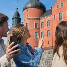 To personer kigger på en mobiltelefon foran en bygning