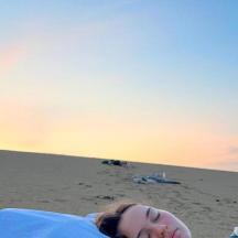 una dona estirada a la platja amb