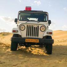 un jeep conduint per la sorra del desert