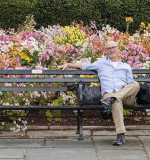 a man sitting on a bench in front of flowers