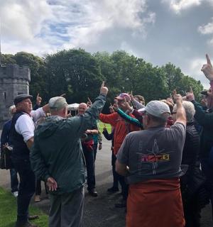 skupina lidí stojící před hradem