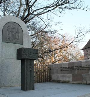 a tombstone in front of a fence with a building