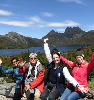 a group of people sitting on a rock with their hands in the air