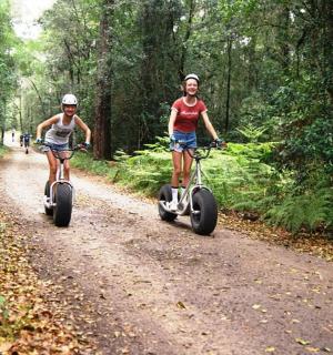 two people riding bikes on a dirt road