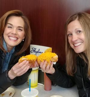 dvě ženy sedící u stolu se dvěma párky v rohlíku