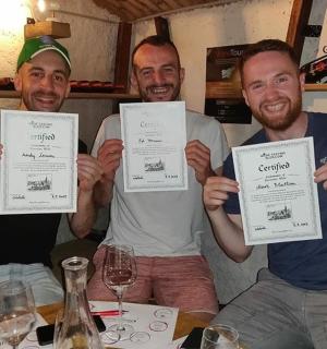 tři muži držící u stolu papírové certifikáty