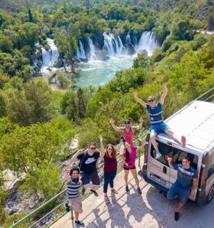 skupina lidí stojící na visutém mostě s dodávkou