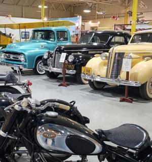 a group of old cars and motorcycles in a garage