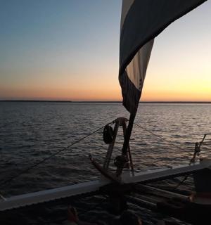 a boat in the water with the sun setting