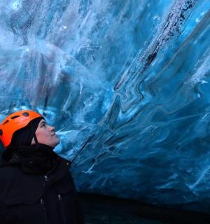 一名女子站在冰洞前