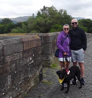 a man and a woman standing next to a wall with a dog