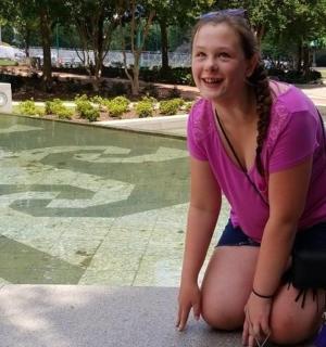 dívka klečící na zemi vedle fontány