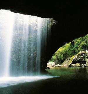 a waterfall in a cave with a body of water