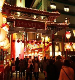 a crowd of people walking down a street at night