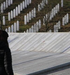 žena kráčející před řadou hrobů