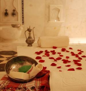 a room with red petals on a table with a bowl and a pile