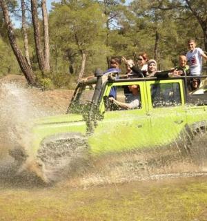 一群人乘坐一辆绿色吉普车在水中