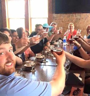 skupina lidí sedících kolem stolu a popíjejících víno