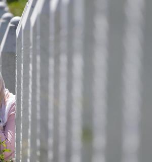 a woman is leaning against a white fence