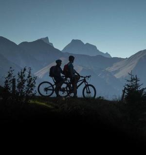 两个人在山上骑自行车，背景是群山