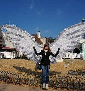 一位女子站在风车前，张开翅膀