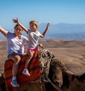 two people riding on the back of a camel