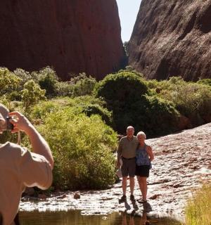 muž fotografující tři lidi jdoucí po řece