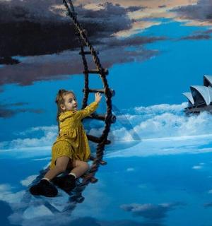 a young girl is sitting on a swing in front of a painting