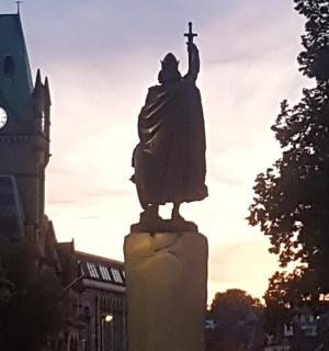 a statue in front of a building with a clock tower