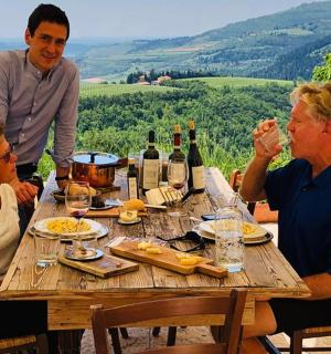 一群人围坐在一张摆满酒瓶的木桌旁