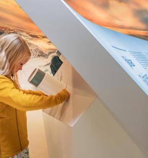 a young girl reading a book at an art exhibit