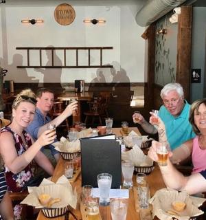 skupina lidí sedících u stolu a pijících pivo