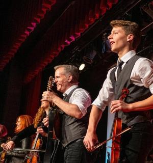 Dva muži stojí na pódiu a hrají na hudební nástroje