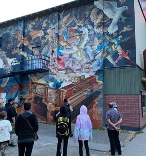 skupina lidí stojících před nástěnnou malbou na budově