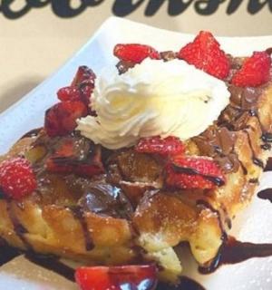 a waffle with strawberries and whipped cream on a plate