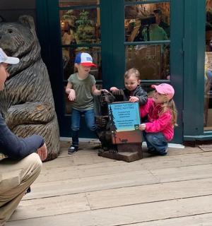 two children playing with a sign in front of a bear statue