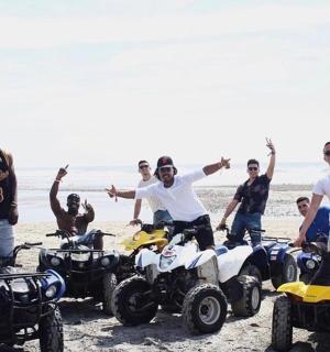 一群男子站在海滩上的四轮摩托车上